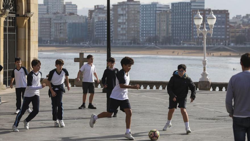 Niños jugando al fútbol en el Campo Valdés, a la puerta de la iglesia de San Pedro. | Pablo Solares