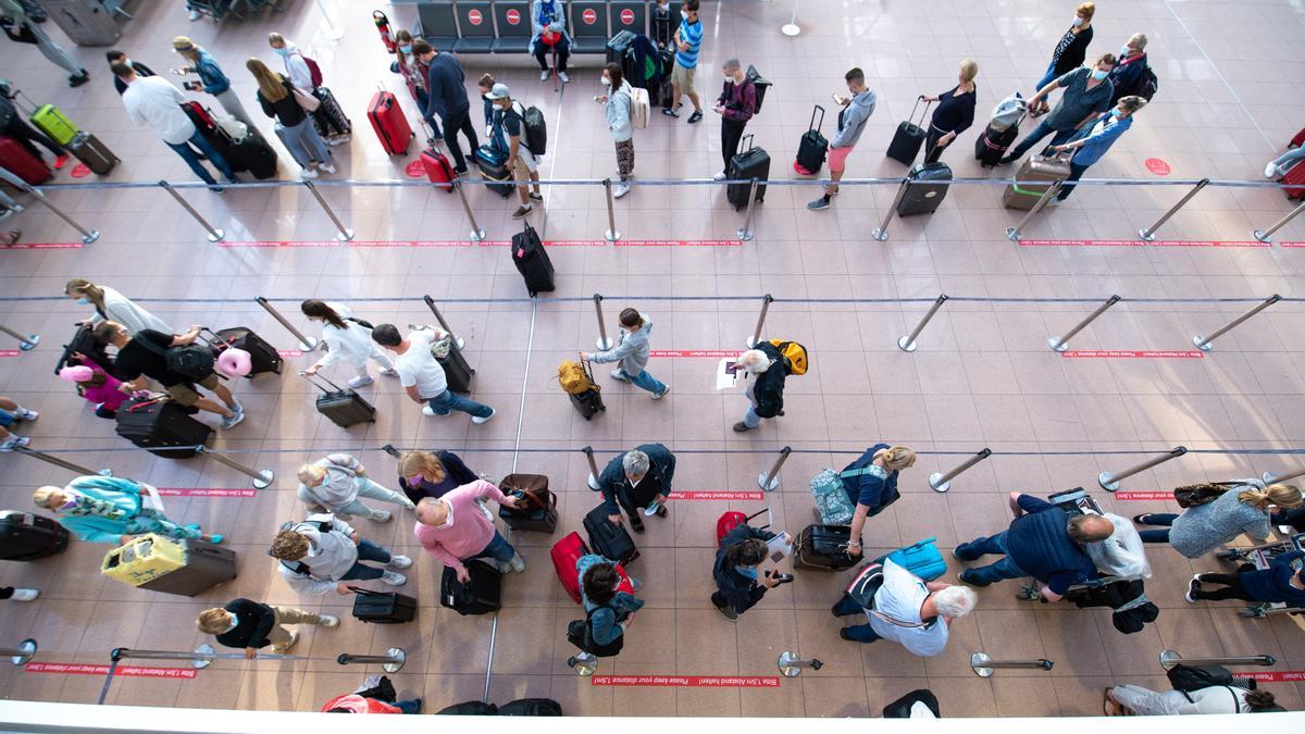 Flugreisende stehen am Flughafen Hamburg Schlange.