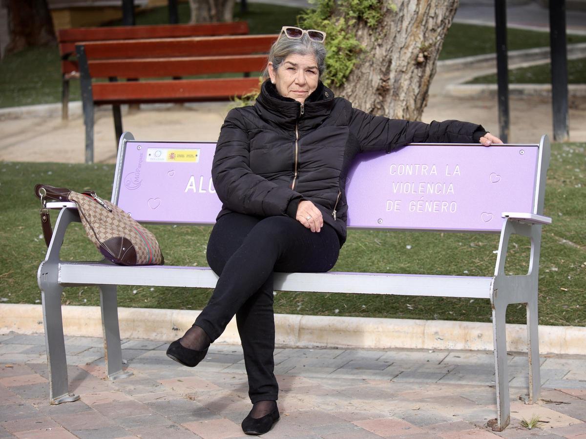 Isabel, sentada en un banco morado de un parque de Alcantarilla y que incluye un mensaje contra la violencia de género, este lunes.
