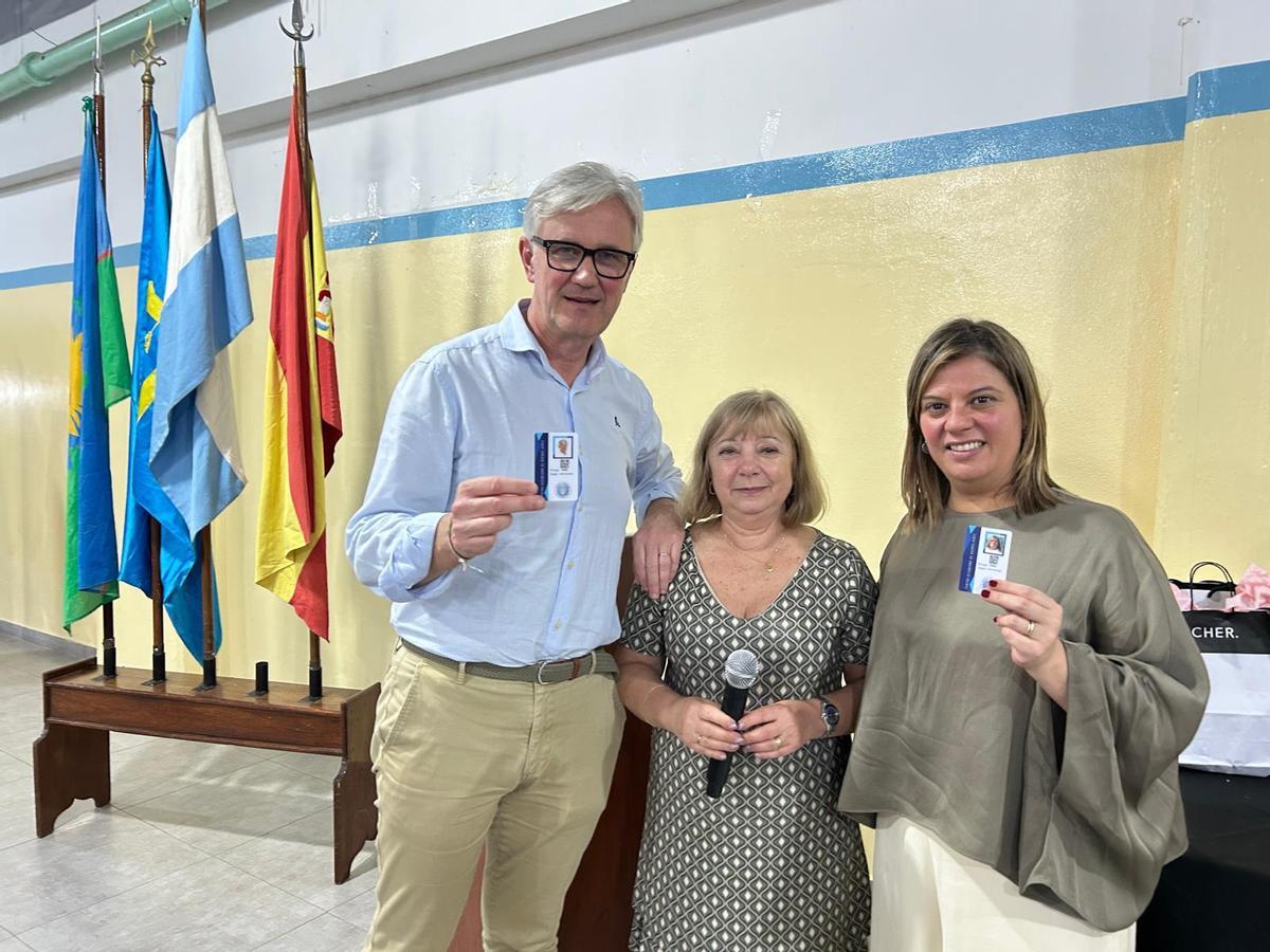 Marcos Niño y Gimena Llamedo muestran sus carnets de socios de honor del Centro Asturiano de Buenos Aires junto a la presidenta de la entidad, Pilar Simón.
