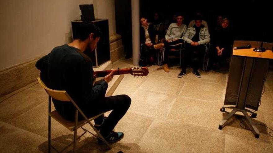 Uno de alumnos toca la guitarra observado por compañeros.