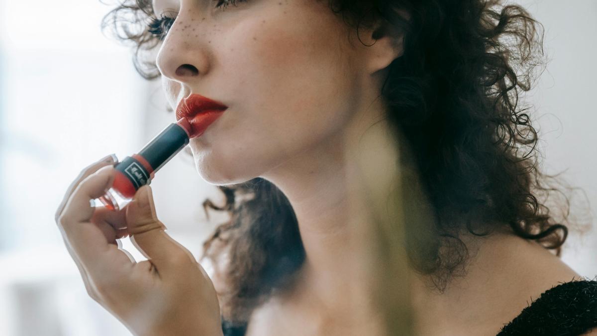 Una chica se pinta los labios de rojo.