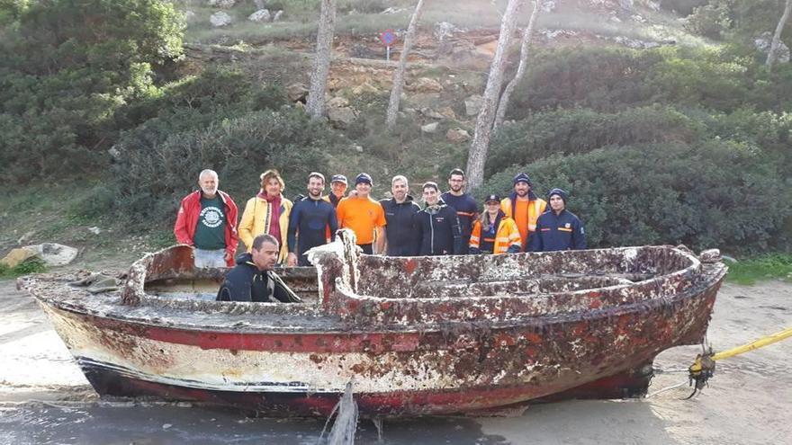 Participantes junto a los restos de una embarcación recogida.