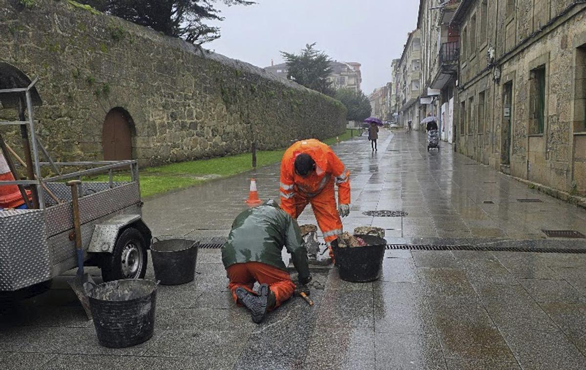Operarios reparando baldosas en Vilagarcía, esta mañana.