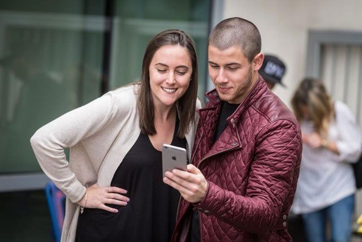 Nick Jonas mira la foto que se ha hecho con una fan