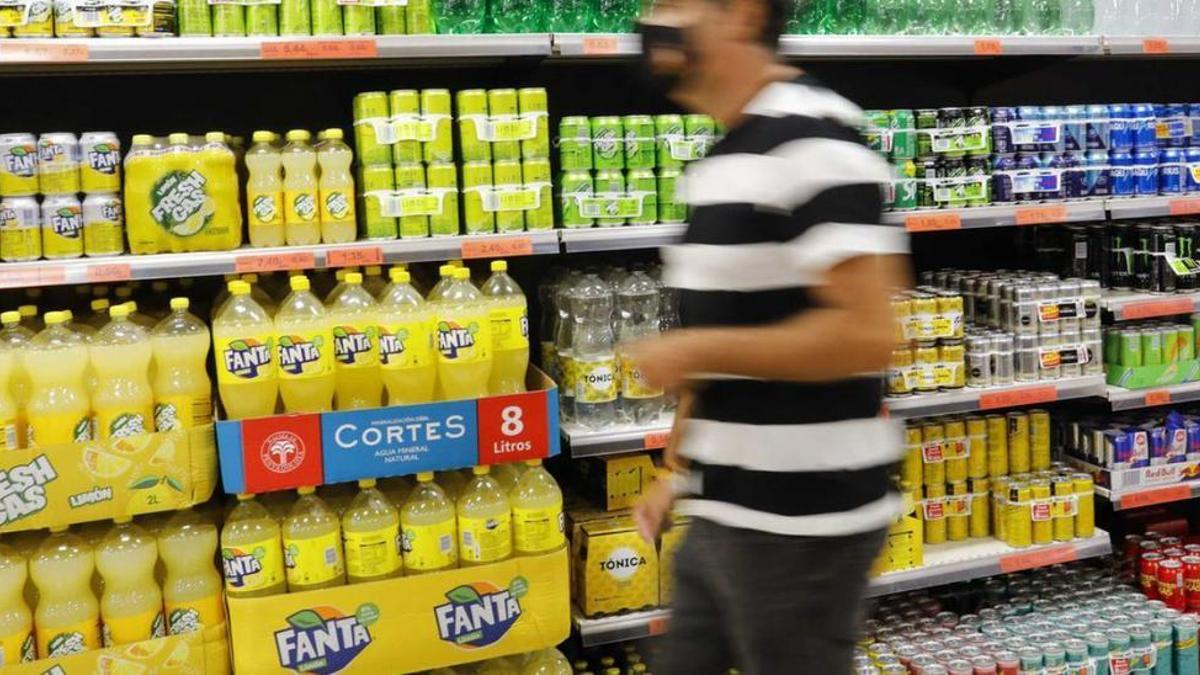 Un hombre pasa frente a los lineales de refrescos de un supermercado.