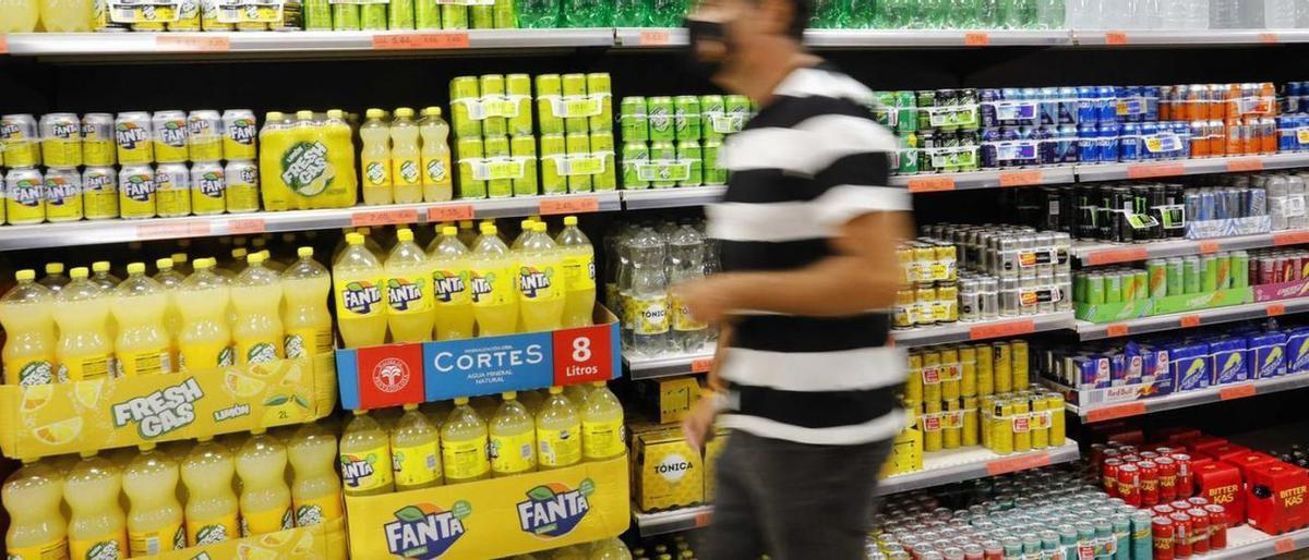 Un hombre pasa frente a los lineales de refrescos de un supermercado.