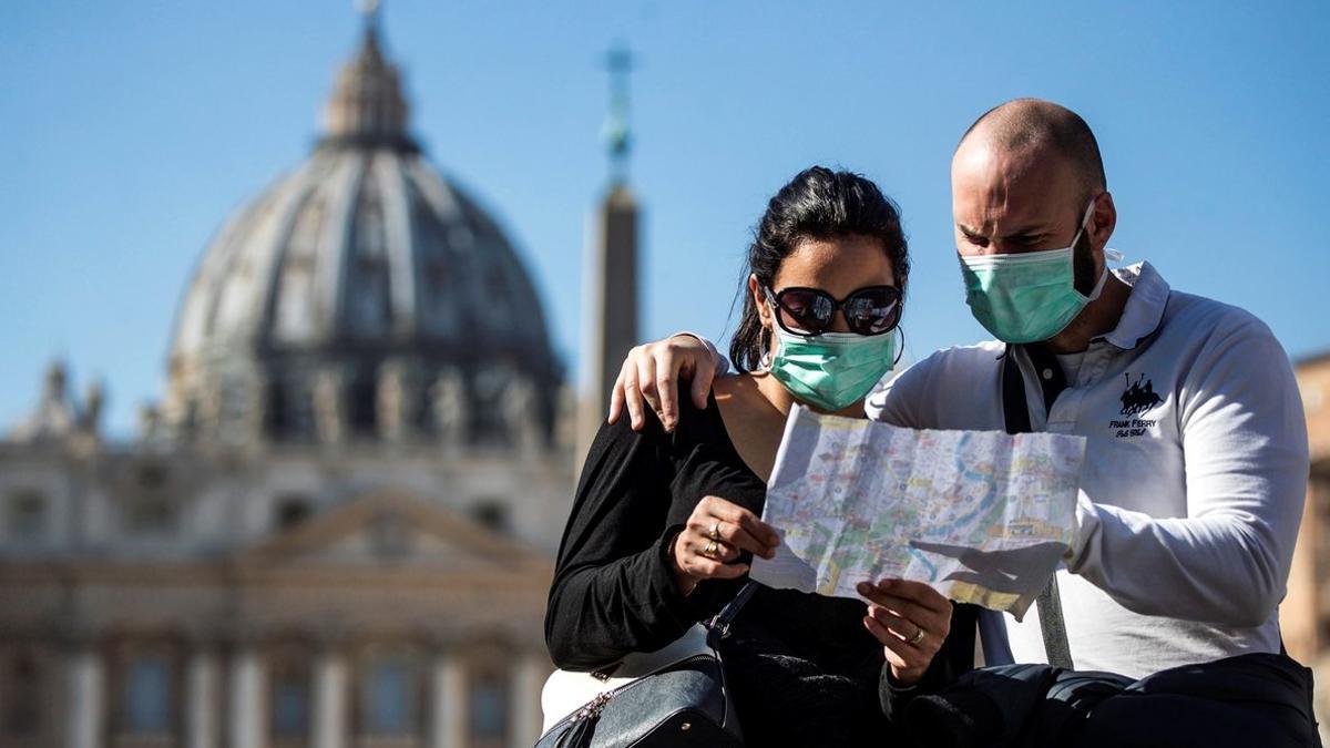 Una pareja de turistas con máscaras protectoras visita la plaza de San Pedro, en el Vaticano