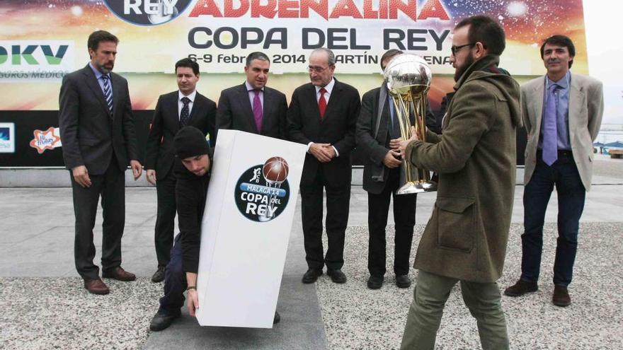 Un operario traslada el trofeo de la Copa, mientras otro coloca el atril ante la expectante mirada de los responsables de la ACB y los rectores de la ciudad.
