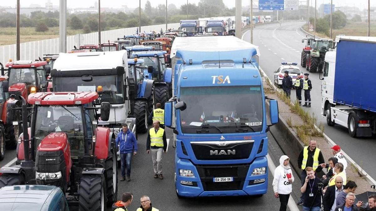 Trabajadores portuarios, camioneros, granjeros y residentes protestan en la autopista, este lunes, en Calais.