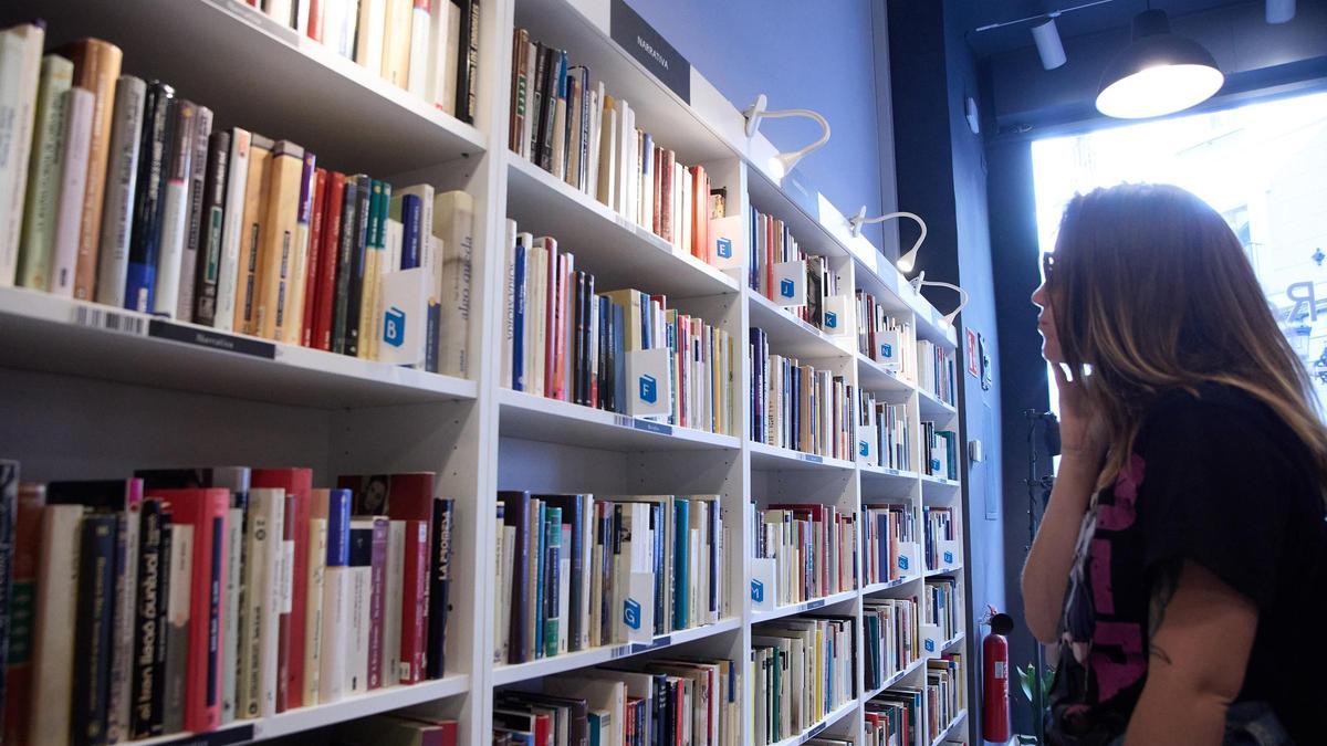 Una mujer mira estanterías en una librería.