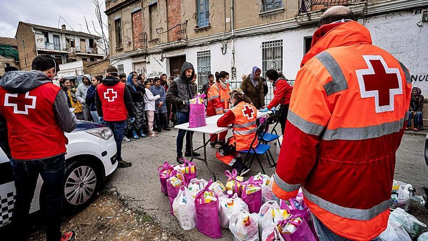 Miembros de Cruz Roja reparten comida en uno de los núcleos de infravivienda.