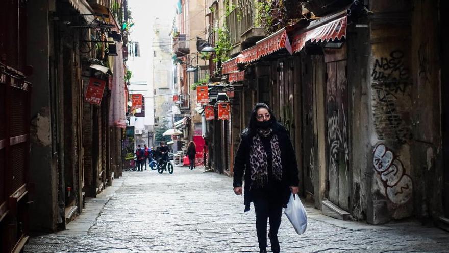 Una mujer camina con mascarilla por una calle de Nápoles.