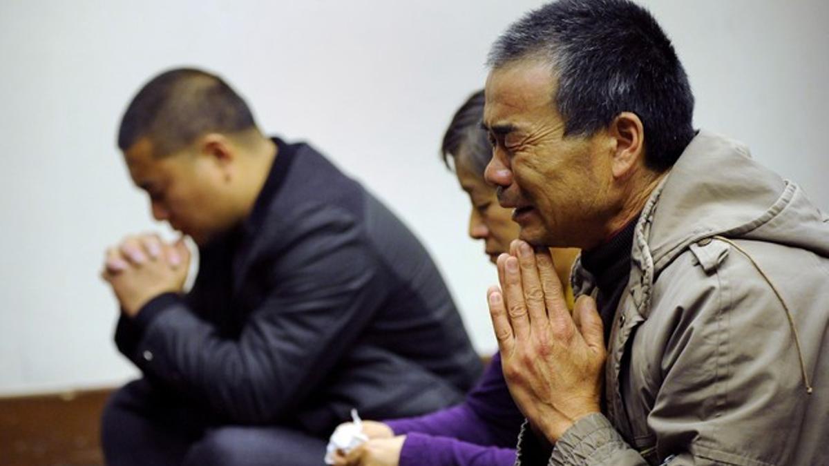 Familiares de los pasajeros del vuelo de Malaysia Airlines rezan, en un hotel de Pekín.