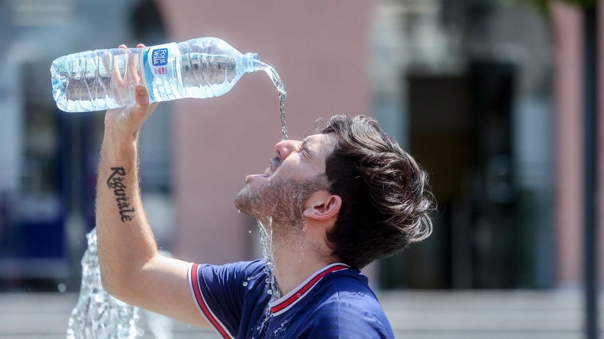Un joven se tira una botella de agua por encima para combatir el calor.
