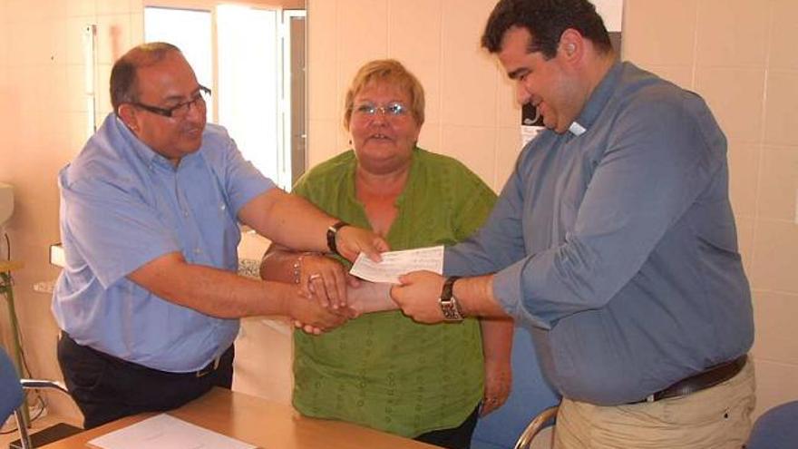 El sacerdote recibe el cheque de manos del presidente de la ONG Recicla Alicante.