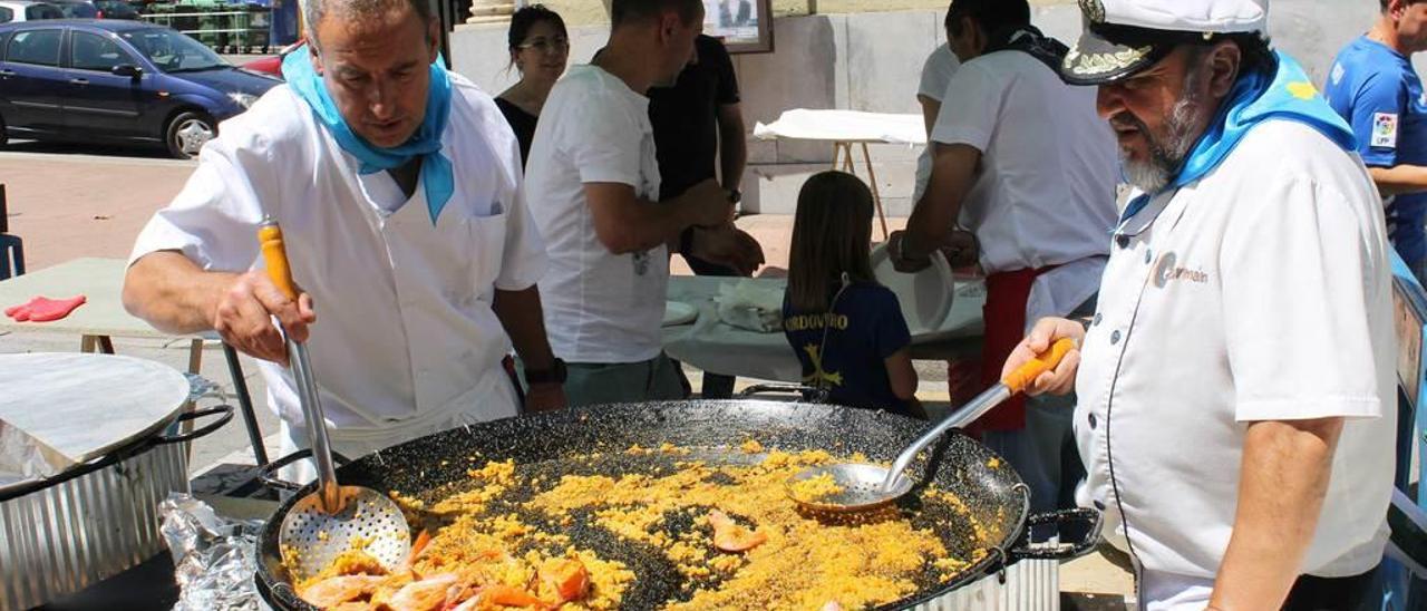 Álvaro Díaz y Germán Prendes &quot;El Buzo&quot; sirven la paella de bogavante que cocinaron.