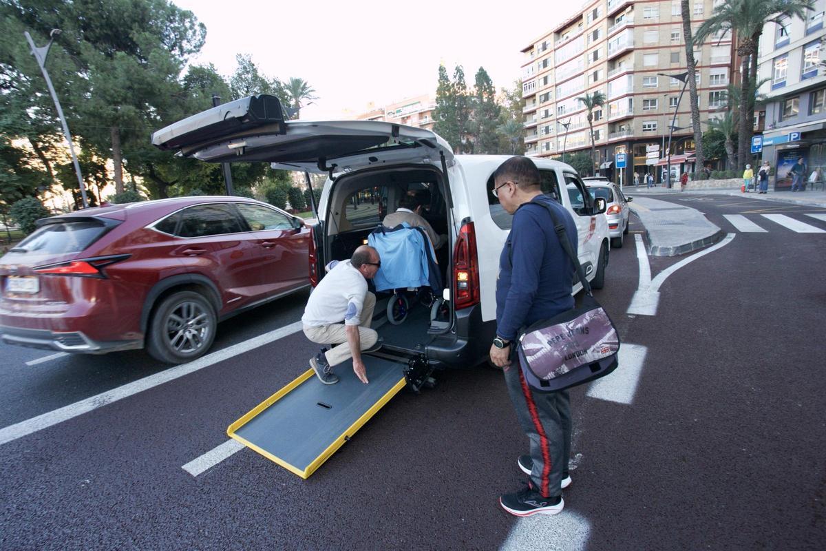 El conductor de un eurotaxi ayuda a su usuario a subir al vehículo.