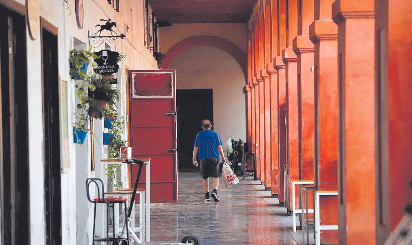 Un hombre camina bajo los soportales de la plaza grande.