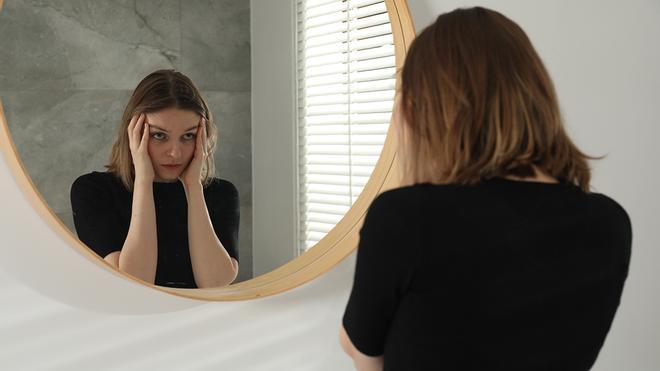 Mujer preocupada frente al espejo
