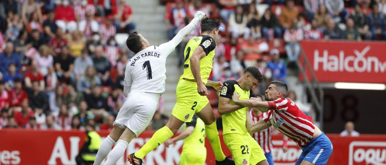 Entre Juan Carlos i Bernardo miren de refusar una pilota penjada a l’àrea del Girona durant el partit de diumenge a Gijón. | LA NUEVA ESPAÑA