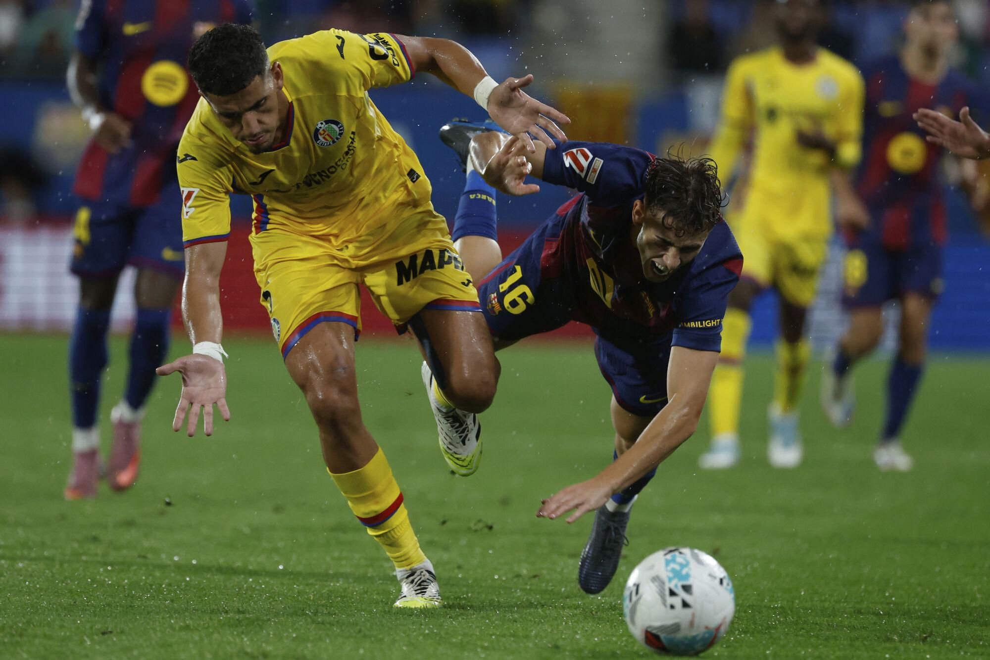 Getafe's Abdel Abqar fights for the ball against Barcelona's Fermin Lopez during a Spanish La Liga soccer match between FC Barcelona and Getafe at the Johan Cruyff stadium in Barcelona, Spain, Sunday, Sept. 21, 2025. (AP Photo/Joan Monfort)