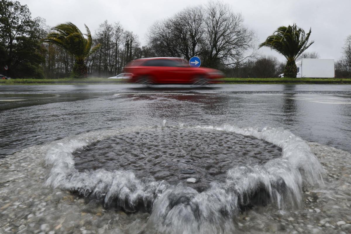 Alcantarilla desbordada por el paso de la borrasca Nils en una calle de Santiago de Compostela.
