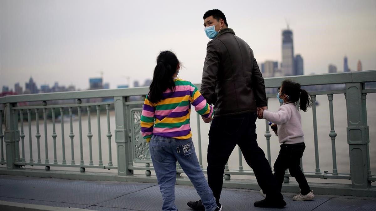 Un adulto y dos niños cruzan el puente de Wuhan, capital de Hubei, en China.