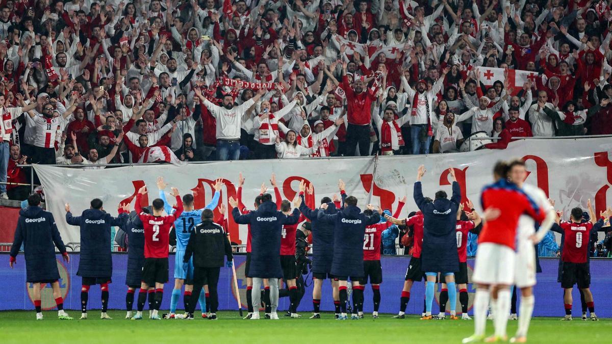 Futbolistas y aficionados georgianos festejan juntos el triunfo en Luxemburgo.