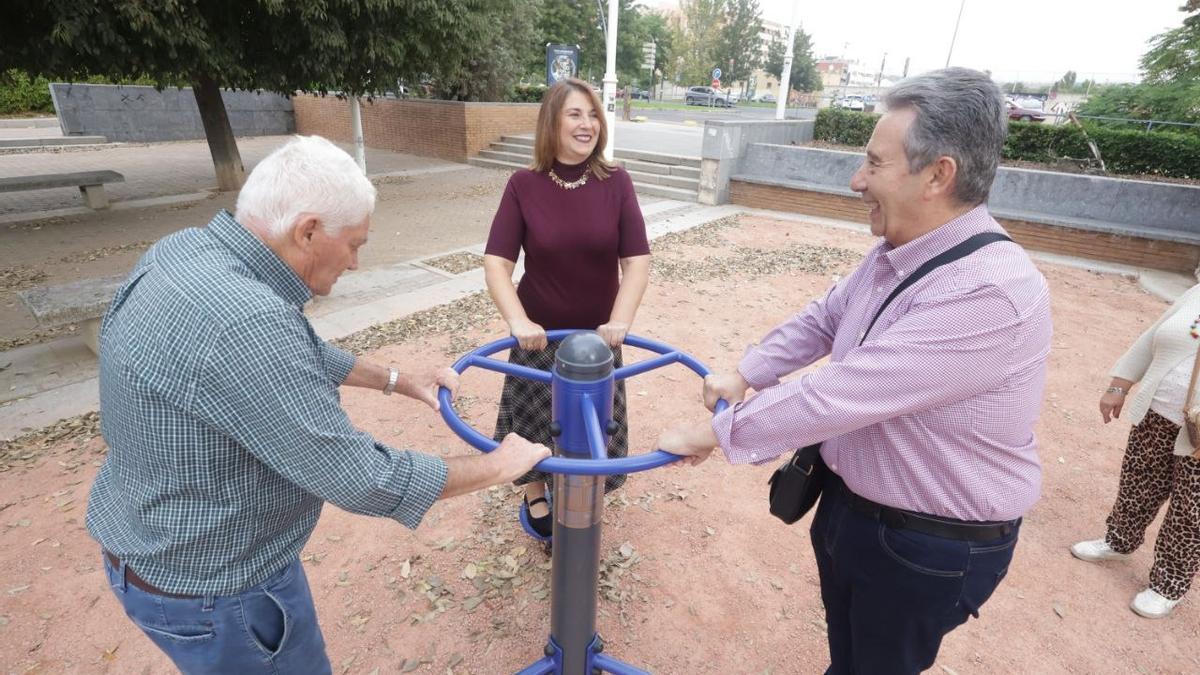 Dos usuarios junto a la concejal Eva Contador en uno de los aparatos para gimnasia al aire libre del parque biosaludable de la calle Montellano.