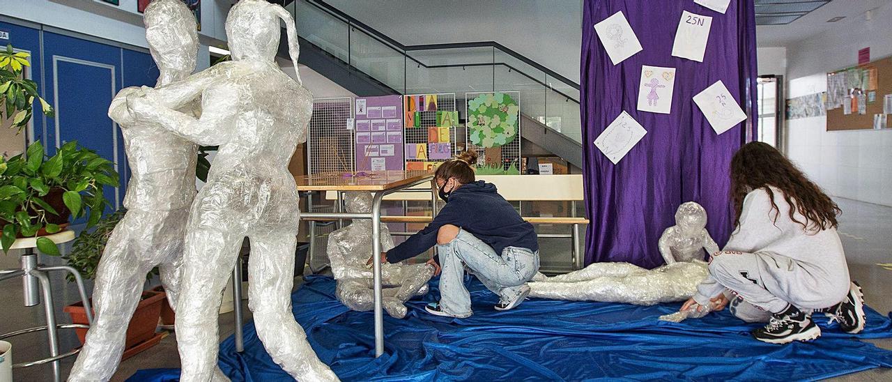 Dos estudiantes entre las figuras plastificadas con las que el instituto denuncia y conciencia contra la violencia de género.