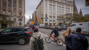 Peatones esperan que un coche y una bici pasen para poder cruzar. En realidad deberían pasar ellos y el coche y la bici, esperar.