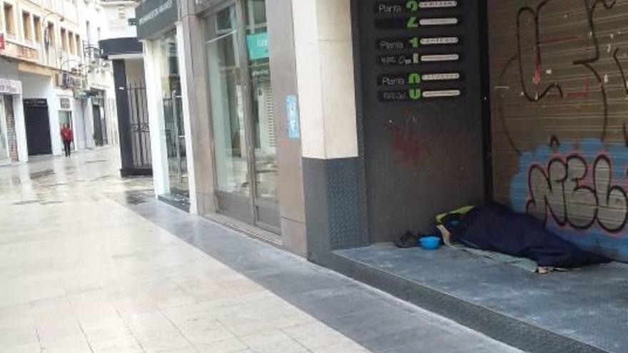 Una persona duerme en el portal de un local en Gandia.