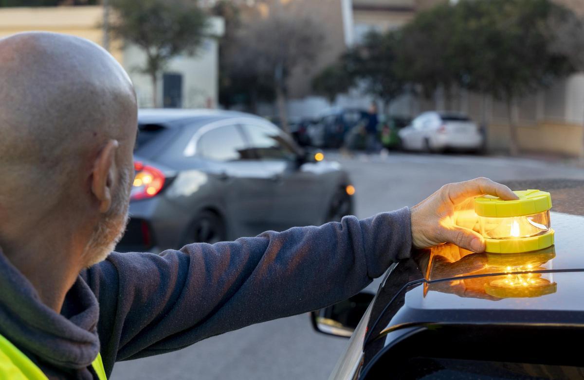 Un ciudadano coloca una baliza sobre su vehículo.