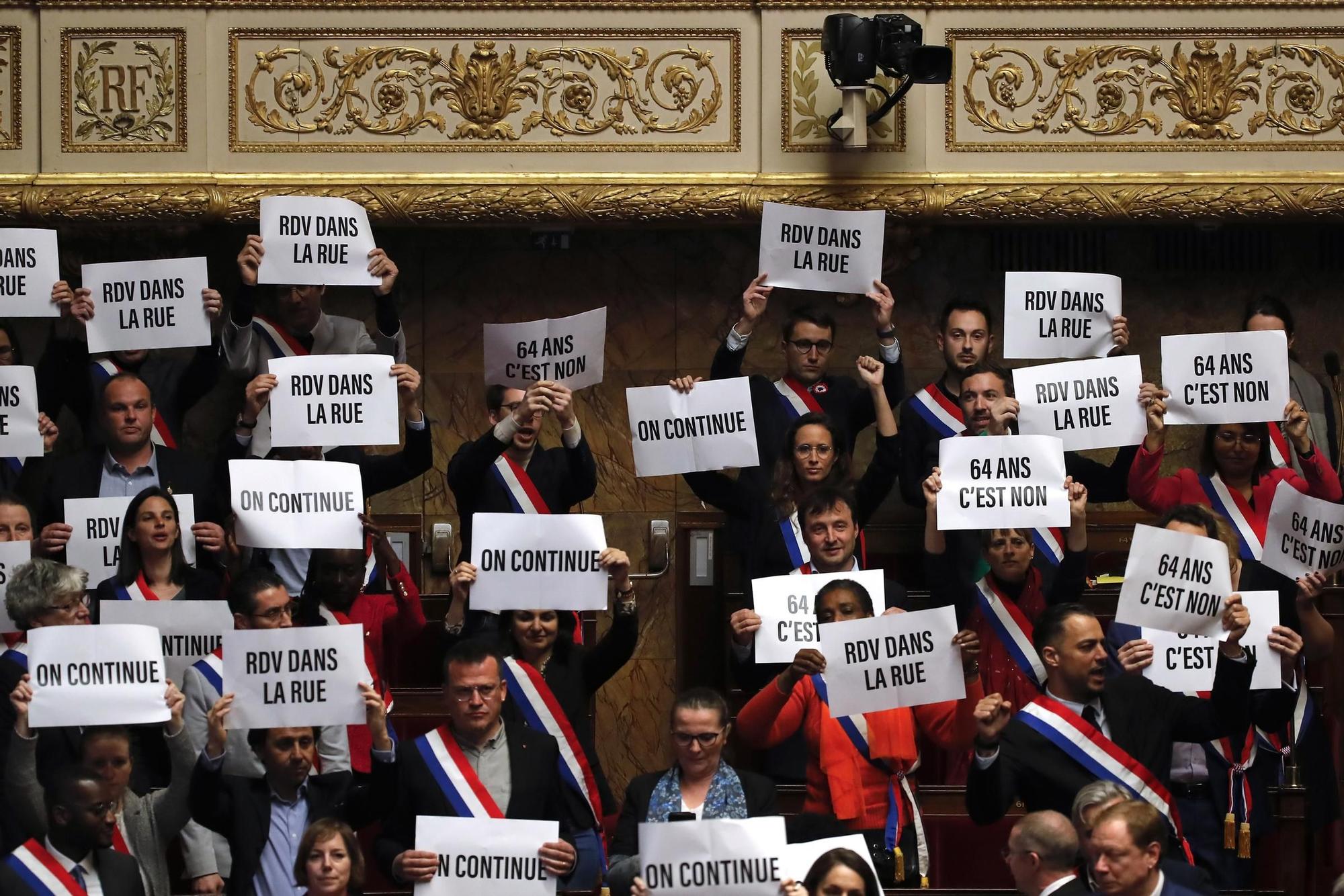 Diputados de izquierda muestran carteles contra la reforma de las pensiones tras fracasar la moción de censura contra el Gobierno francés, este lunes.