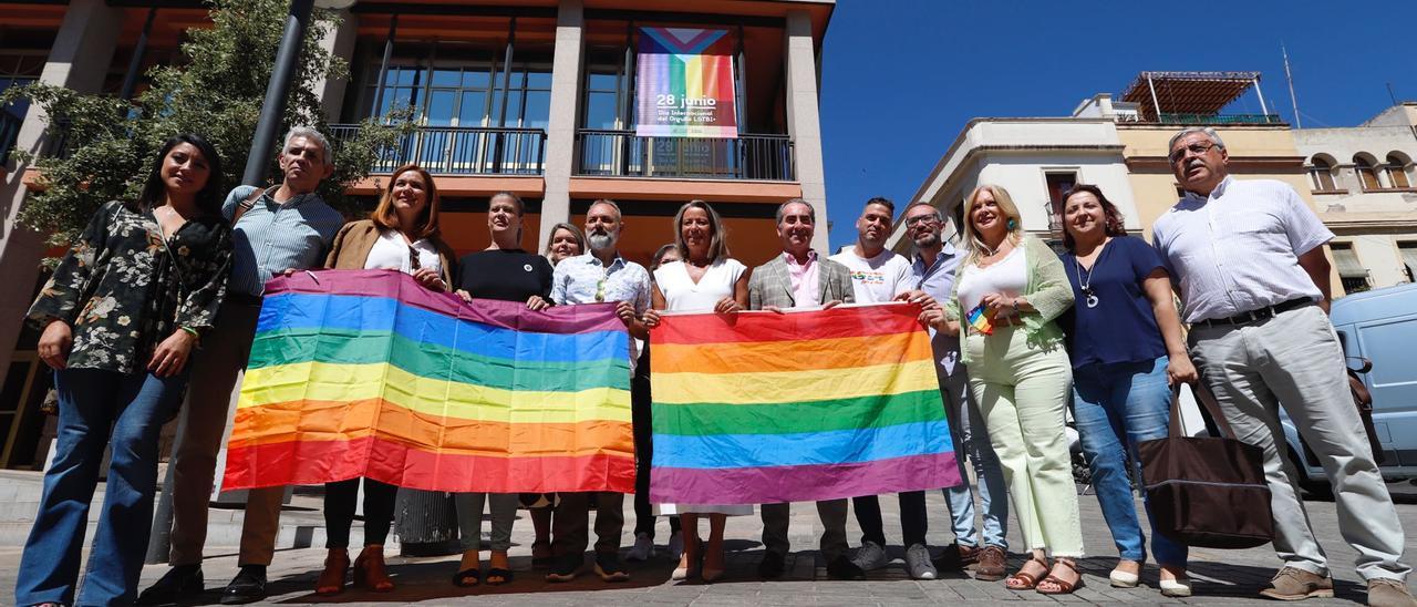 Representantes del gobierno municipal y de asociaciones locales LGTBI+ despliegan la bandera del arcoíris frente al Ayuntamiento