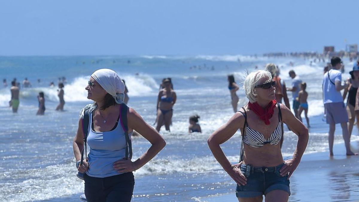 Dos turistas pasean por la orilla en Playa del Inglés, en el Sur.