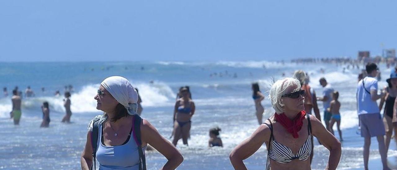 Dos turistas pasean por la orilla en Playa del Inglés, en el Sur.