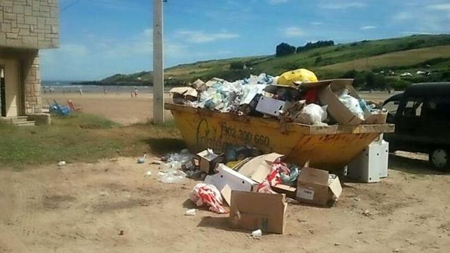 Un contenedor de obra lleno de basura, ayer, en la playa de Bañugues.