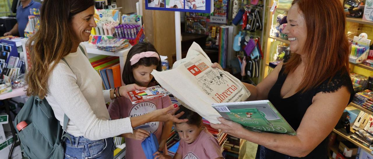 Una familia recoge sus libros de texto en la librería Cativos. / ALBA VILLAR