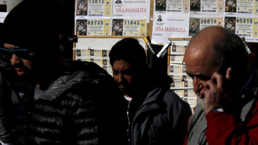 Diverses persones davant d&#039;un punt de venda de loteria.