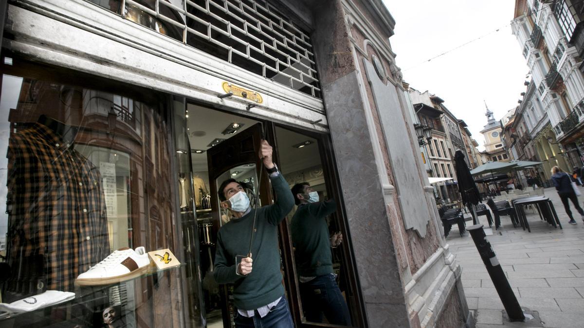 Juan Prado baja la persiana de su tienda en la calle Cimadevilla, en Oviedo.