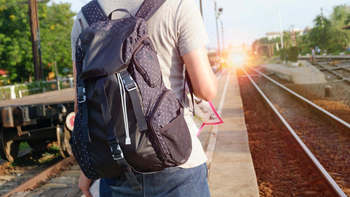 Un joven, mapa en mano, se prepara para un viaje en tren.