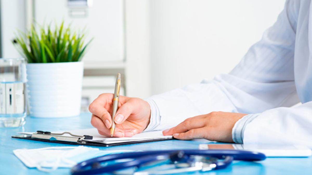 Un metge fent un informe en una consulta en una imatge d'arxiu.