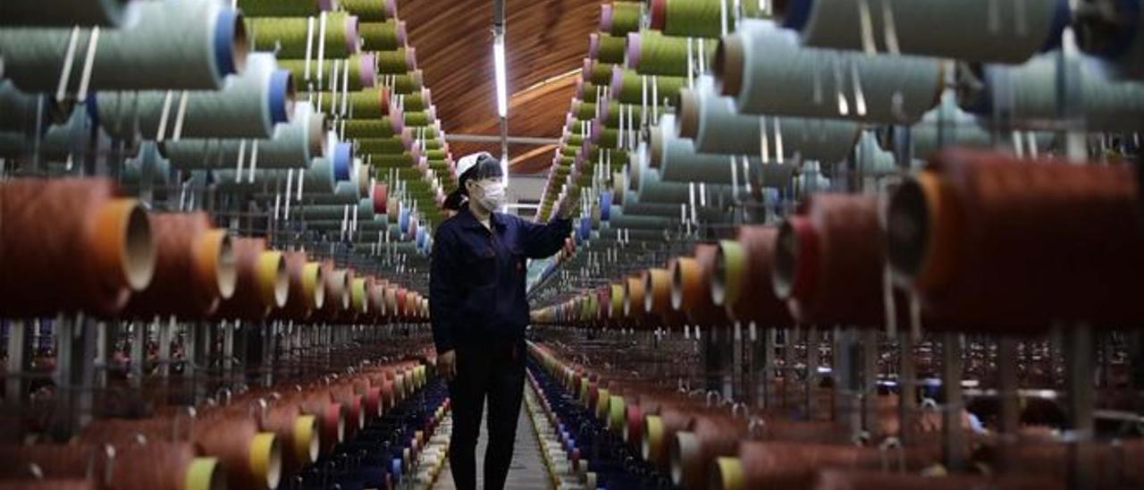 Una empleada vigila unos cilindros en una fábrica textil china.