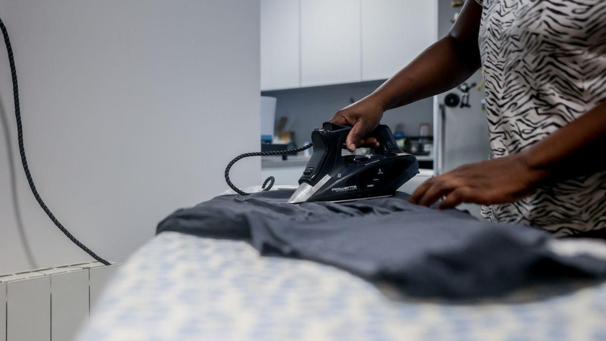 Una empleada de hogar plancha una camiseta, el día en que han aprobado el paro para las empleadas del hogar.