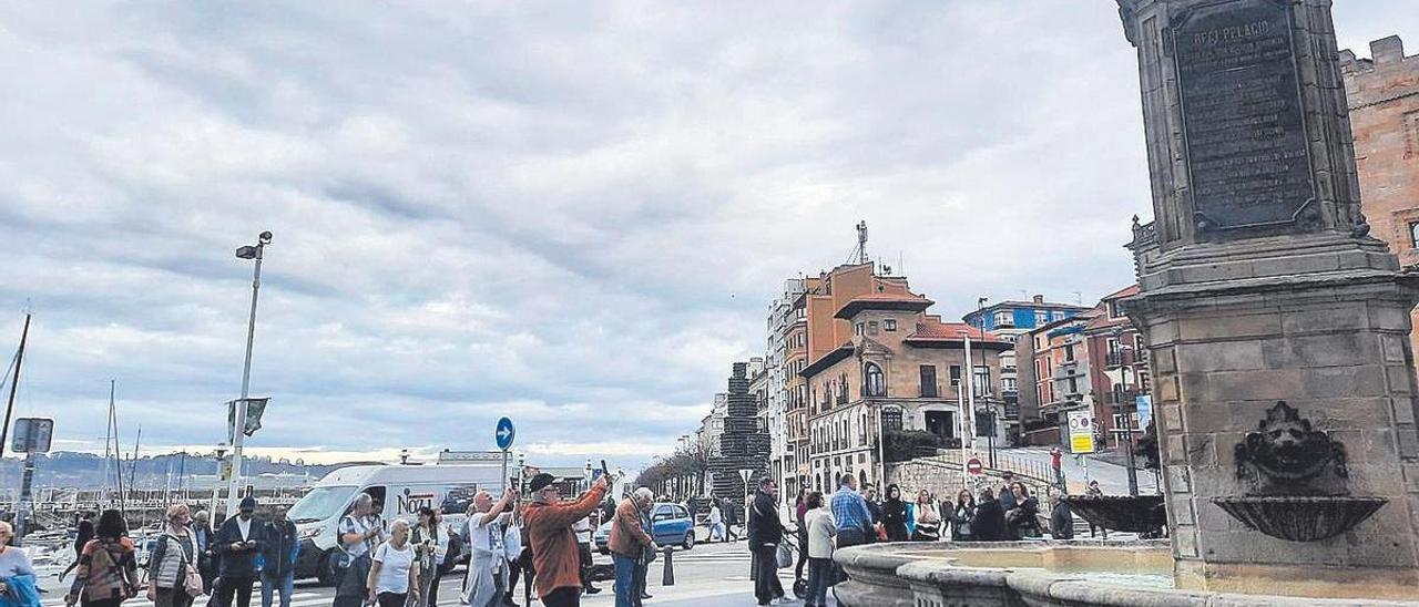 Un grupo de turistas, ayer por la mañana, haciéndose fotografías ante la estatua de Pelayo, en la plaza del Marqués.