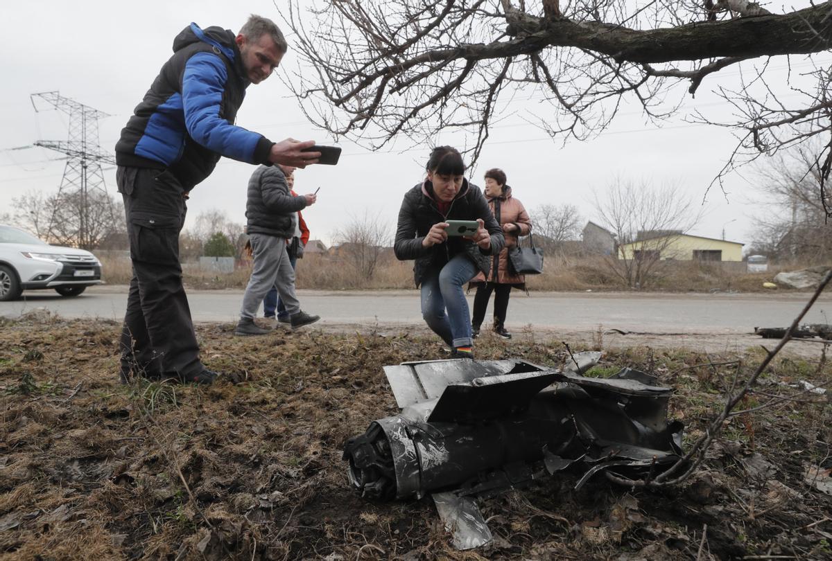 Un grupo de gente toma fotos de los restos de un misil en las calles de Kiev, tras una noche de bombardeos en la ciudad.