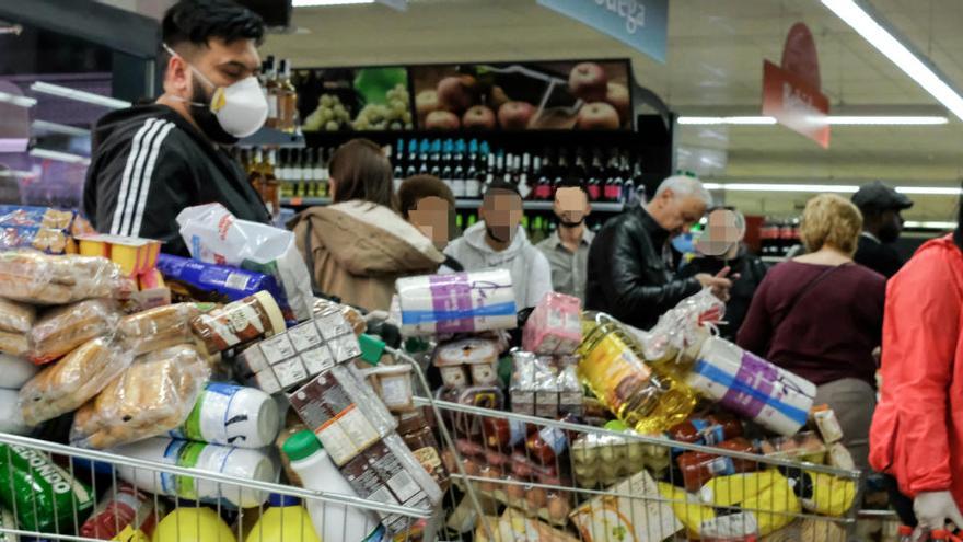 Consumidors amb mascareta amb carros de supermercat plens a vessar