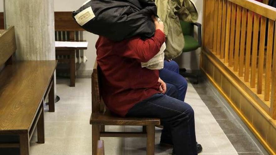 Los Hermida, tapándose con sus abrigos en un juicio en 2017. // A.V.